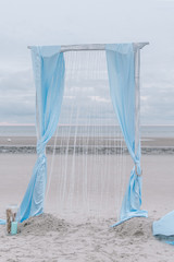 Vintage pastel blue wedding arch on the beach background. Outdoor ceremony decoration concept. Northsea, Germany, Sankt Peter-Ording.
