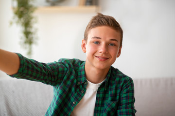 Handsome teen boy taking selfie while spending time at home