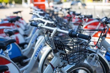 Bicycles stand on a parking for rent in city in the summer