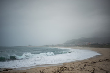 entferntes Haus an stürmischen Strand mit Brandung