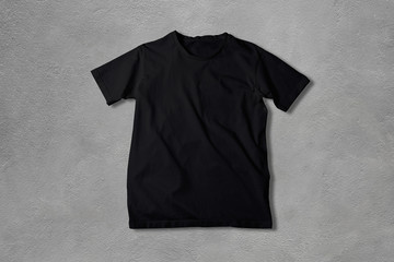 Basic black Tshirt on concrete background. Mock up for branding t-shirt. 
