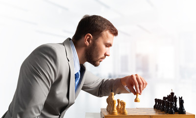 Businessman moving chess figure in chessboard