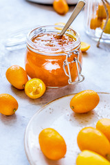 kumquat on plate and jam in jar at gray background