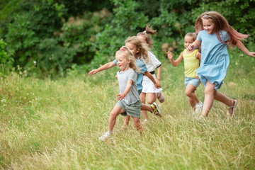 Naklejka na ściany i meble Angels. Kids, children running on green forest. Cheerful and happy boys and girs playing, laughting, running through green blooming meadow. Childhood and summertime, sincere emotions concept.