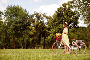 Fototapeta na wymiar Young woman with bicycle in meadow