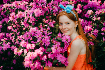 Obraz na płótnie Canvas Portrait of attractive young girl in a summer dress enjoys of the purple plants in the botanical garden