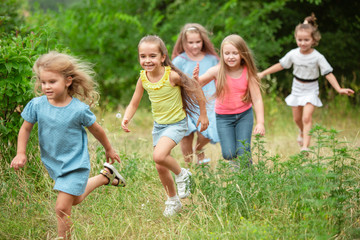 Angels. Kids, children running on green forest. Cheerful and happy boys and girs playing, laughting, running through green blooming meadow. Childhood and summertime, sincere emotions concept.