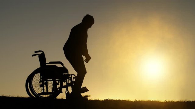 Disabled man gets up from the wheelchair and raises his hands up