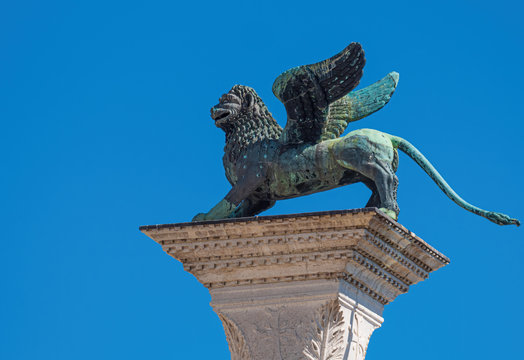 The ancient winged lion of St. Mark in front of the Doge's palace on its high plint - Venice, Italy