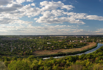Obraz premium general plan panoramic photo of the urban village landscape, with the river and houses. Green City. Against the backdrop of a cloudy sky with white clouds.