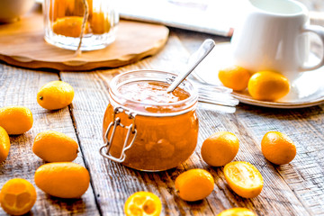 kumquat on plate and jam in jar at wooden table