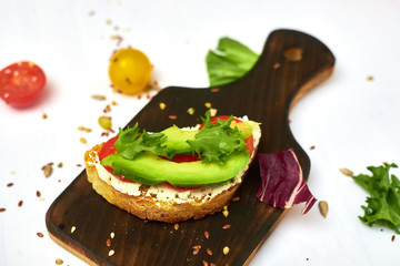 Ciabatta with avocado and different vegetables on a white background.