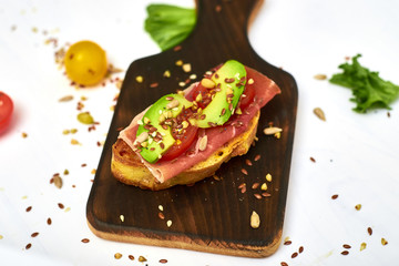 Ciabatta with avocado and different vegetables on a white background.