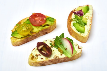 Ciabatta with cream cheese, avocado, various vegetables. Vegetarian sandwiches on a white background.