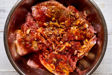 Raw rabbit in a bowl with spices. Marinate meat, preparing for cooking.