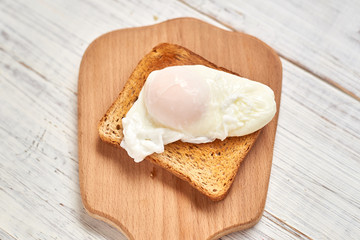 Toast with poached egg on a white plate.