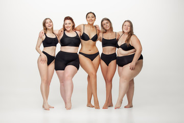 In love with myself. Portrait of beautiful young women with different shapes posing on white background. Happy female models. Concept of body positive, beauty, fashion, style, feminism. Diversity.