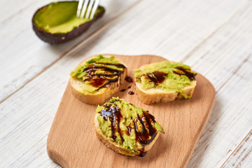 Baguette, bruschetta, canapes with avocado and maple syrup on a light wooden background.