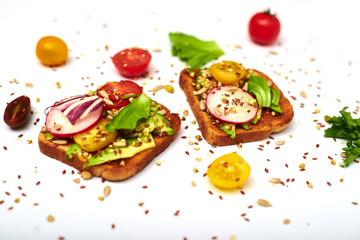 Toasts with vegetables, avocado, tomatoes, a set of seeds on a white background. Healthy food, diet concept.