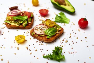 Toasts with vegetables, avocado, tomatoes, a set of seeds on a white background. Healthy food, diet concept.