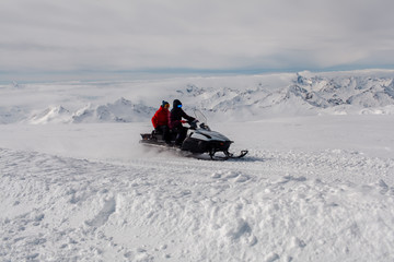 Fototapeta na wymiar snowmobile on the background of mountain peaks