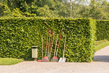 Gartenwerkzeuge stehen an einer Hecke im Park
