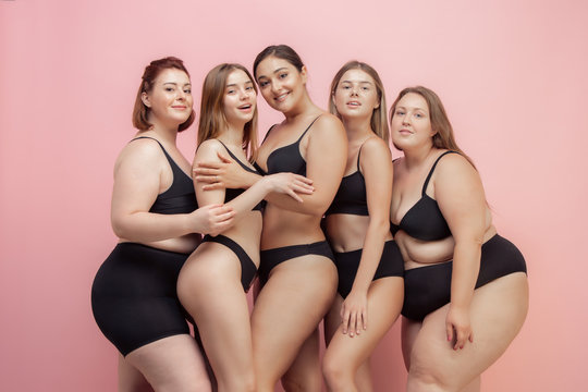 Loves herself and feels good. Portrait of beautiful young women with different shapes posing on pink background. Happy female models. Concept of body positive, beauty, fashion, style, feminism