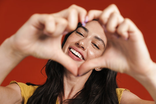 Image of caucasian smiling woman making heart gesture