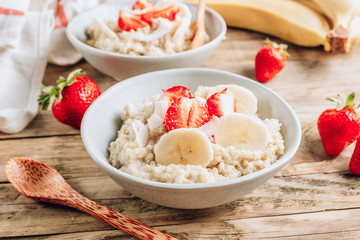 Quinoa porridge with coconut milk and fresh strawberries on wooden rustic background. Healthy Lactose and Gluten Free Breakfast.