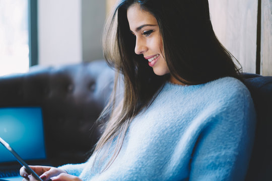 Cropped image of beautiful hipster girl browsing internet websites on touch pad connecting to free 4G internet.Smiling student sitting indoors with modern digital tablet and enjoying leisure time