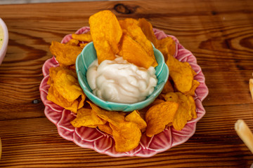 Crispy orange sweet potato chips in vintage plate with mayonnaise on wooden table, top view. Unhealthy eating concept.