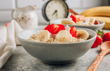 Quinoa porridge with coconut milk and fresh strawberries on light gray background. Healthy Lactose and Gluten Free Breakfast.