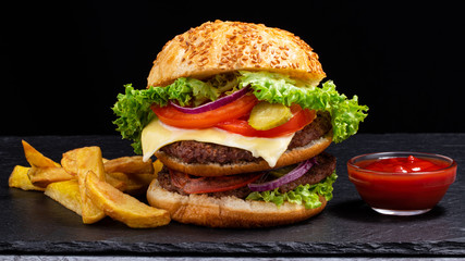 Big burger with french fries on dark background