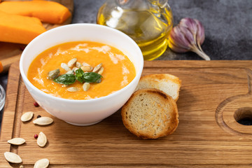 Pumpkin and carrot soup with cream and pumpkin seeds on  wooden background