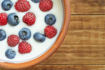 Yogurt with blueberries, raspberries, blackberries, flax seeds on a wood background. Served vegetarian dish. Healthy breakfast, healthy food. Background for menu of restaurants, cafe.