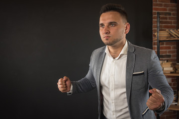 young attractive business man showing blank copy space over palm for customer to add item or text, looks happy and excited, isolated on dark background in white shirt