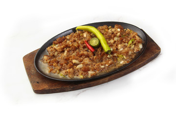 Filipino dish called Sisig or chopped pig face served with egg and chilli on a sizzling plate