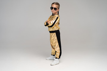 Happy little girl in gold suit dancing isolated on white background