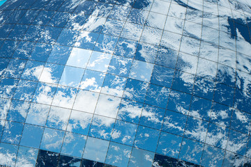 blue sky and clouds reflecting on a covering of square glass blocks
