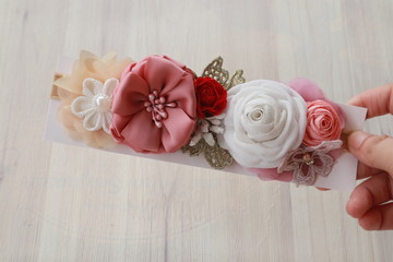 A hand holding bouquet of flowers made out of fabric cloth textile in beautiful pastel colors that can be used as hair accessory, decoration, and embellishment