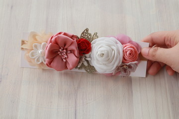 A hand holding bouquet of flowers made out of fabric cloth textile in beautiful pastel colors that can be used as hair accessory, decoration, and embellishment