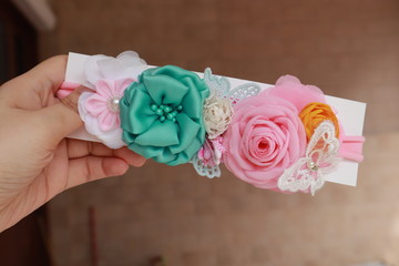 A hand holding bouquet of flowers made out of fabric cloth textile in beautiful pastel colors that can be used as hair accessory, decoration, and embellishment