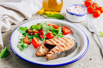 Grilled Pink salmon steak and salad on concrete background. Healthy food concept.