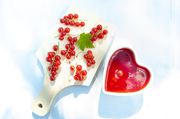 Red and ripe red currants  and heart shaped bowof berry jam, flat lay. Harvest and cooking theme