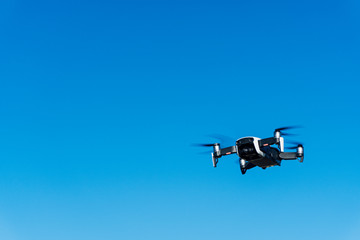 Generic image of a white drone flying across a blue sky. Remote control equipment for aerial surveillance.