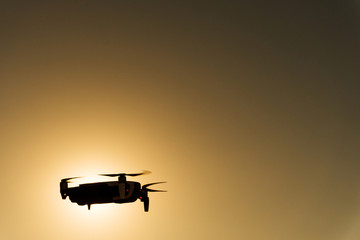 Silhouette of a drone in the air on a warmly colored sunset