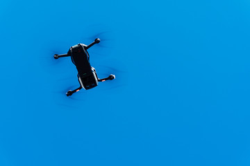 View of a quadricopter drone from below flying over a blue sky. background of a cloudless sky