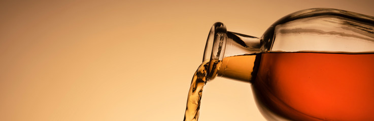 a bottle of whiskey, Bourbon, or liqueur. pouring liquid, a stream from the neck. close - up orange...
