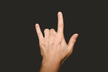 The man's hand holding his finger shows the symbol I love you on a black background.