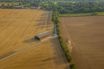 Panorama aerial view of countryside in Schleswig-Holstein with tractor fertilizing the field,...